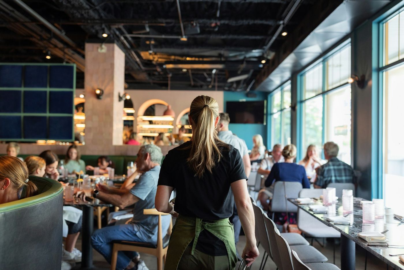A busy restaurant with a waiter walking between full tables