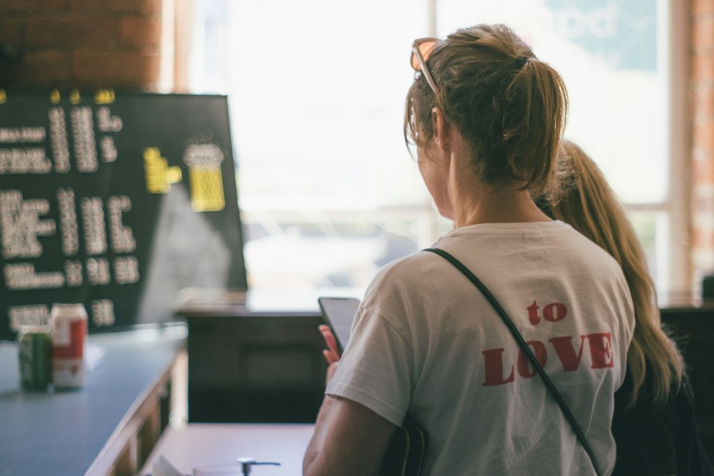A woman at a cafe counter checking her phone