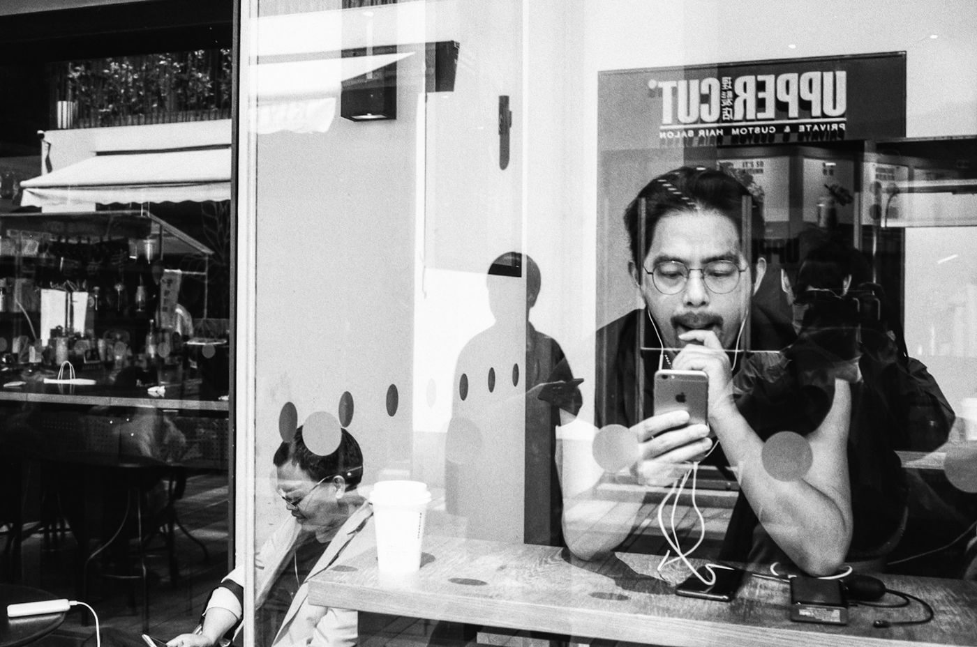 A man at a cafe window reading an answer on his phone